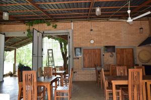 a restaurant with wooden tables and chairs and a brick wall at Elephant Arcade Yala in Tissamaharama