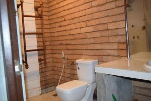 a bathroom with a toilet and a brick wall at Elephant Arcade Yala in Tissamaharama +35 photos