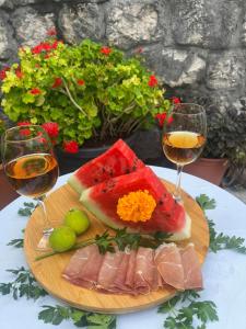 a plate of watermelons and wine glasses on a table at Holiday home Raduš in Virpazar