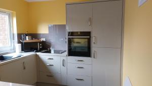 a kitchen with white cabinets and a white refrigerator at Gidansu in Penrith