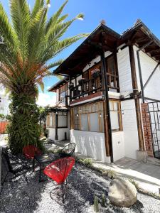 a house with chairs and a palm tree in front of it at Modern Apartment with Private Balcony in Quito