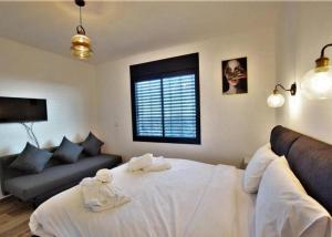 a bedroom with a large white bed and a couch at ממלכת החלומות - וילה מהממת עם בריכה פרטית מחוממת מקורה ונוף מהמם in ‘Ein el Asad +18 photos