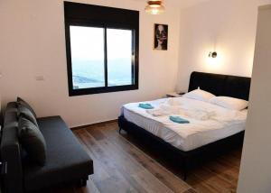 a bedroom with a bed and a couch and a window at ממלכת החלומות - וילה מהממת עם בריכה פרטית מחוממת מקורה ונוף מהמם in ‘Ein el Asad