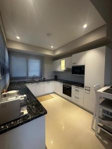 a kitchen with white cabinets and a black counter top at Sifah BF 508B in As Sīfah