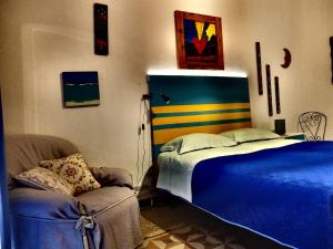 ein Schlafzimmer mit einem blauen Bett und einem Stuhl in der Unterkunft AlCasart in Alcamo