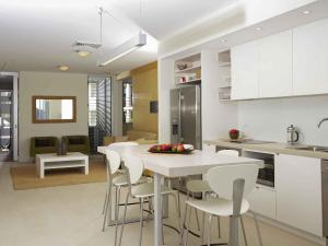 a kitchen and living room with a table and chairs at Grand Mercure Apartments Magnetic Island in Nelly Bay