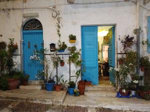 eine blaue Tür in einem Haus mit Topfpflanzen in der Unterkunft AlCasart in Alcamo