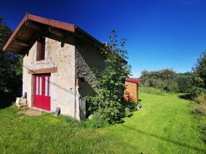 an old building with a red door on a grass field at Maisonnette cocooning, ancien four à pain in Saint-Éloy-la-Glacière +7 photos