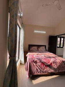 a bedroom with a bed with a red comforter and a window at Namya Villas in Bhīm Tāl