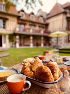 a plate of pastries on a table with cups of coffee at Manoir des Étangs in Croissanville