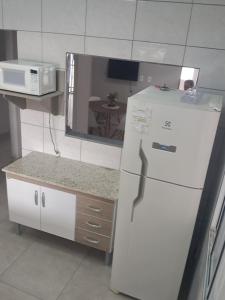 a kitchen with a white refrigerator and a microwave at Casa com piscina Espaço teddy cakes in Campinas