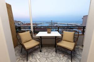 a table and chairs on a balcony with a view of a harbor at Aélia Studios in Agia Ermioni