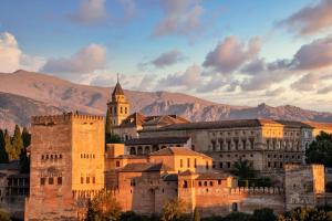 an old building with a clock tower in front of mountains at Casa Montilla in Granada