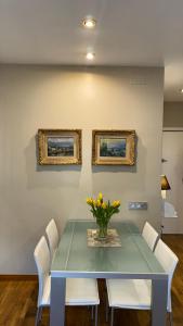 a dining room table with white chairs and a vase of flowers at Petit Rosselló in Barcelona