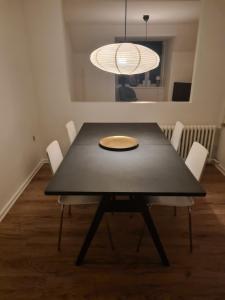 ein schwarzer Esstisch mit weißen Stühlen und einer Leuchte in der Unterkunft Suite 3 in Frederikshavn + 9 Fotos