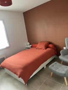 a bedroom with a bed with a orange blanket and a chair at Petite maison calme in Dun-sur-Auron