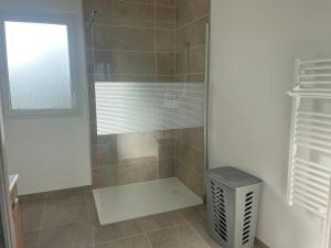 a bathroom with a shower with a window and a trash can at Petite maison calme in Dun-sur-Auron
