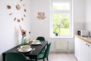 a dining room with a black table and green chairs at N&N Apartments - Studio mit Netflix - Workstation im Zentrum in Schwerin +25 photos