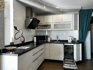 a kitchen with white cabinets and black counter tops at TuttiFruttiaApt in Nerja