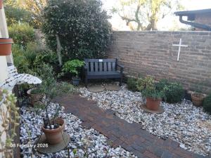 a bench sitting in front of a brick wall with plants at Aroha Guest Apartment in Roodepoort