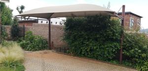 a large umbrella sitting in front of a brick building at Aroha Guest Apartment in Roodepoort