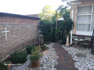 a church yard with a brick wall and a cross at Aroha Guest Apartment in Roodepoort