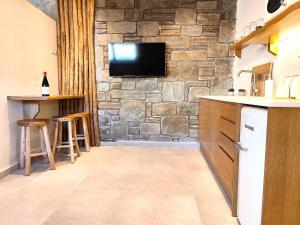 a kitchen with a tv on a stone wall at Megusta Mykonos in Tourlos
