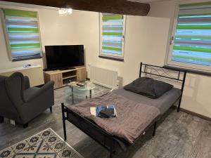 a bedroom with a bed and a chair and a television at Neu! Einfaches Zimmer - einfacher Preis in Lohra, Hessen - low Budget - für Vertreter - Monteure - Wanderer - Radler - nur WC mit Waschbecken ohne Dusche aber günstig in Lohra