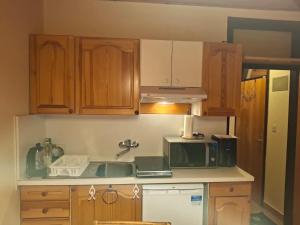 a kitchen with wooden cabinets and a sink and a microwave at Cosy Rogla appartment 108 in Zreče