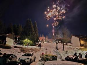 a firework display in the sky with cars parked in the snow at Cosy Rogla appartment 108 in Zreče