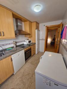 a kitchen with wooden cabinets and a white refrigerator at Apartamentos Residencial Duquesa in San Luis de Sabinillas