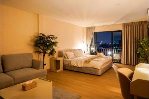 a hotel room with a bed and a couch at Ningle Place Hotel Pathumthani in Ban Pak Khlong Si