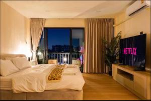 a bedroom with a bed and a tv and a window at Ningle Place Hotel Pathumthani in Ban Pak Khlong Si