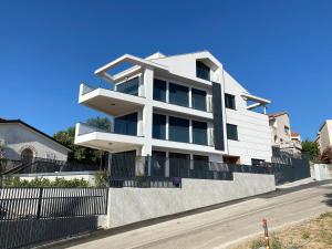 a white house with a fence in front of a street at Marina Penthouse in Punat