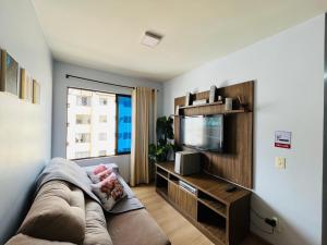 a living room with a couch and a flat screen tv at Apartamento Mobiliado com internet e ar condicionado no centro in Cascavel