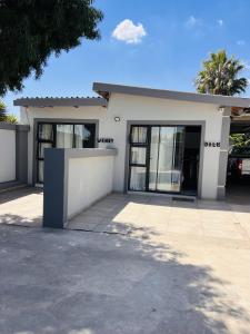 a white house with glass windows and a driveway at Zindiza Guesthouse in eMalahleni
