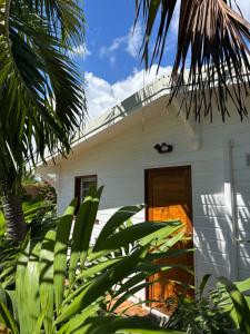 a white house with a door and some plants at Le Frangipanier Cozy Bungalow in Le Moule
