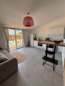 a kitchen and living room with a table and a couch at Le Frangipanier Cozy Bungalow in Le Moule