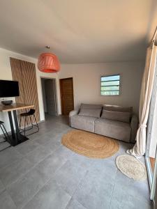 a living room with a couch and a table at Le Frangipanier Cozy Bungalow in Le Moule +16 photos