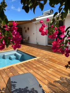 a deck with pink flowers and a swimming pool at Le Frangipanier Cozy Bungalow in Le Moule