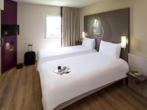 a hotel room with two beds and a suitcase at Hotel Ibis Styles Lleida Torrefarrera in Lleida
