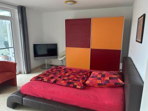 a bedroom with a red bed with a colorful headboard at Garten Wohnung in Singen