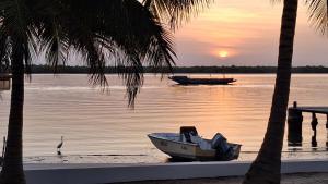 a boat sitting on the shore of a lake at sunset at Residence Coco Plage in Elinkinde