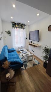 a living room with a blue couch and a flat screen tv at L'écrin de Nature T2 Centre Historique in Auxerre