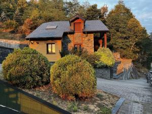 a wooden house with a black roof and some bushes at Les Bosquitos Chalet in Ax-les-Thermes