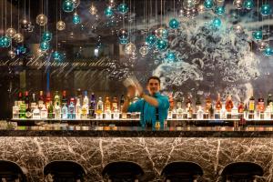 a man standing behind a bar with bottles of alcohol at Motel One Stuttgart-Bad Cannstatt in Stuttgart