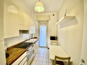 a small kitchen with white cabinets and a table at Anna Home Gallarate train station to Milan Malpensa self-check-in in Gallarate