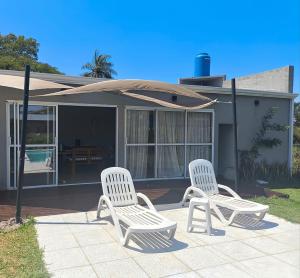 two white chairs sitting in front of a house at Quincho El Solar in Corrientes