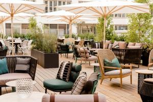 a patio with chairs and tables and umbrellas at Motel One München-Haidhausen in Munich