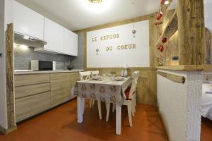 a kitchen with a table with chairs and a refrigerator at LE REFUGE DU COEUR in Pré-Saint-Didier +20 photos